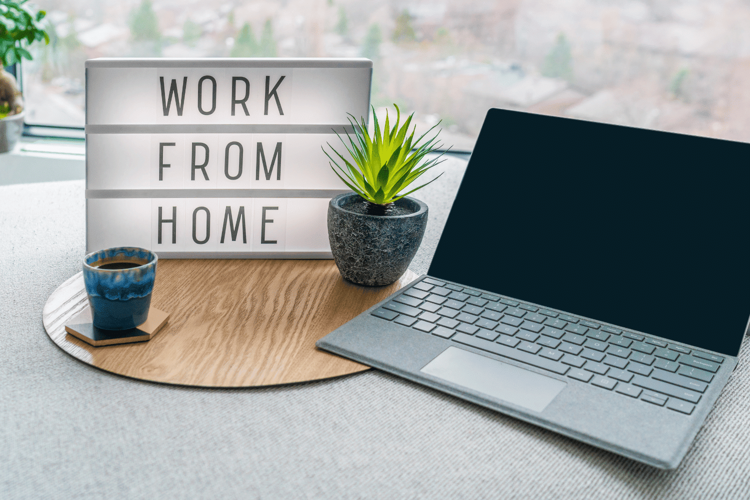 home desk with laptop computer, coffee cup, plants, and sign that says "work from home"