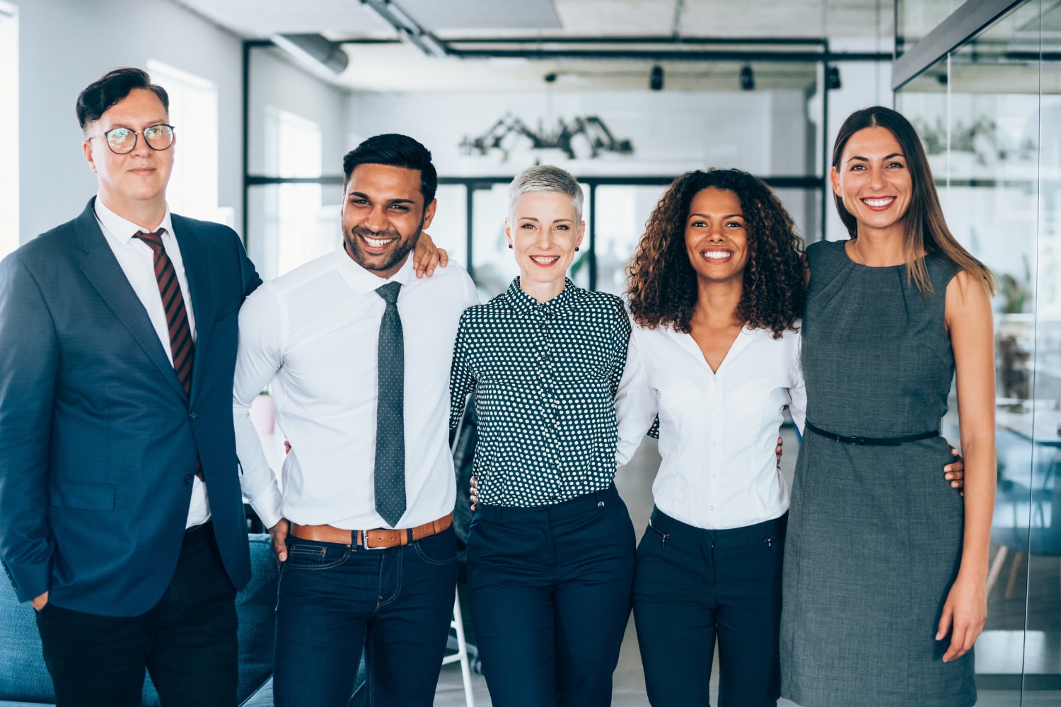 team of five young professionals standing in office setting