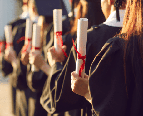 line of college graduates holding up diplomas