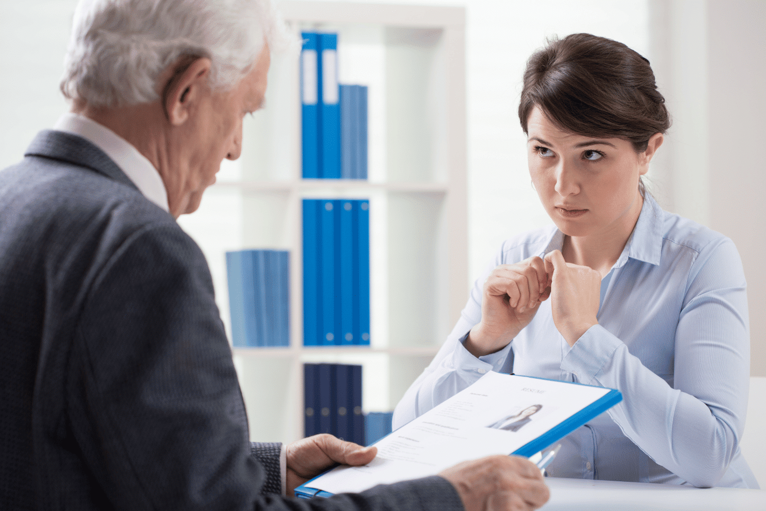 young executive woman being interviewed by older executive man