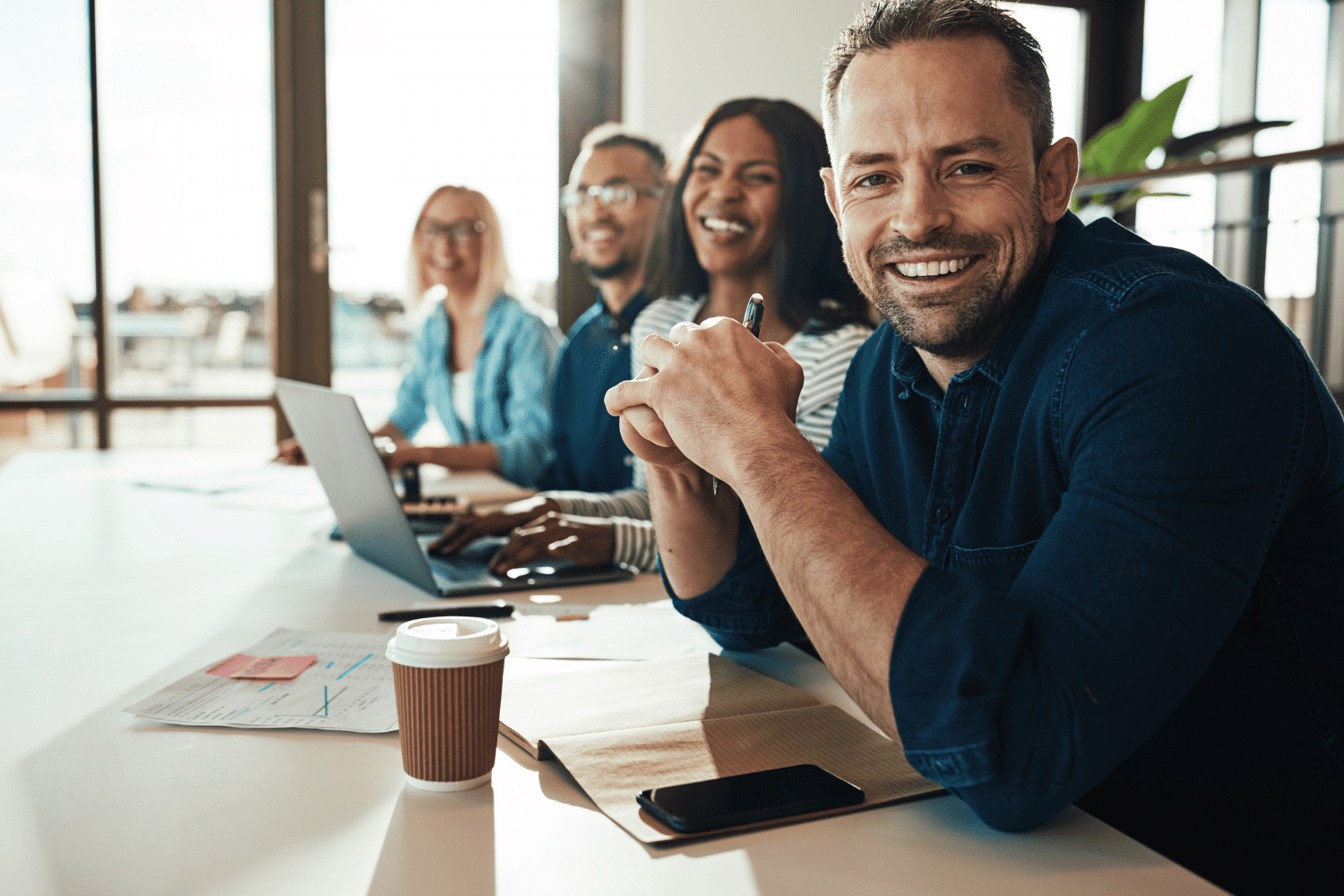 Group of happy professionals working at a conference table together in a great place to work