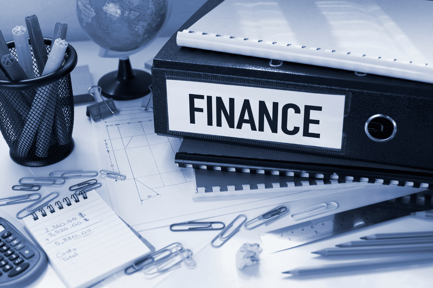 Desk covered with items including binder marked FINANCE