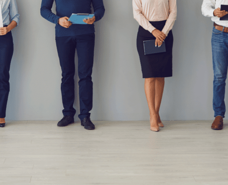 two professional women and two professional men from waist down standing against a wall