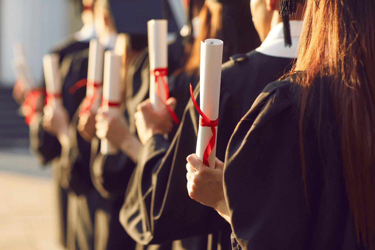 line of college graduates holding up diplomas