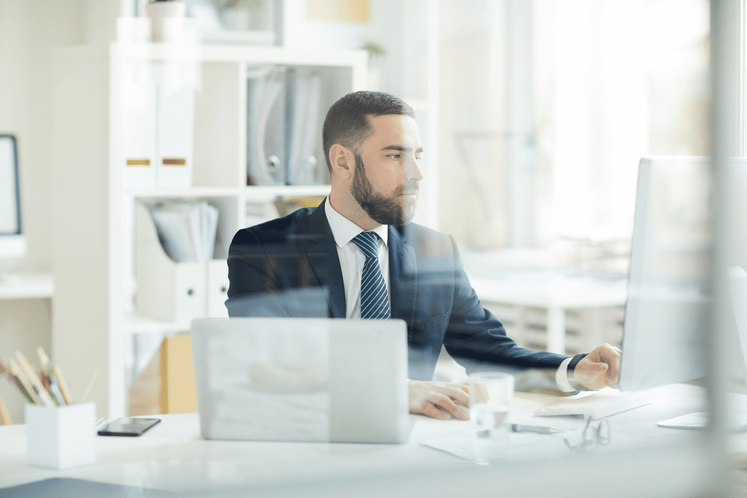 Bearded young professional in suit working at a desk