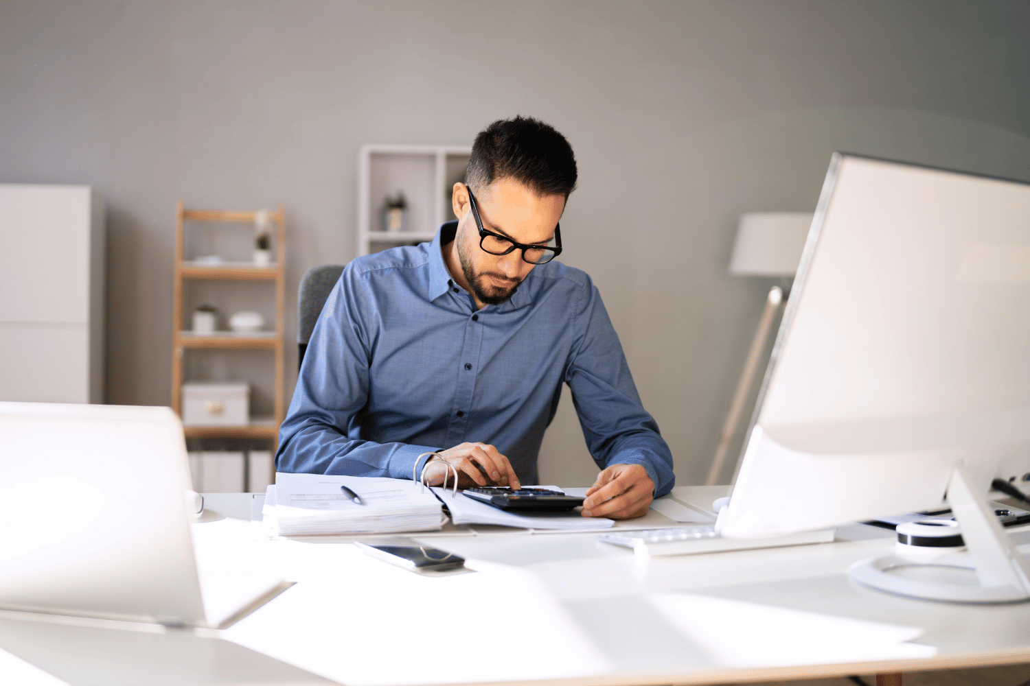 Male accountant working working on calculator in home office