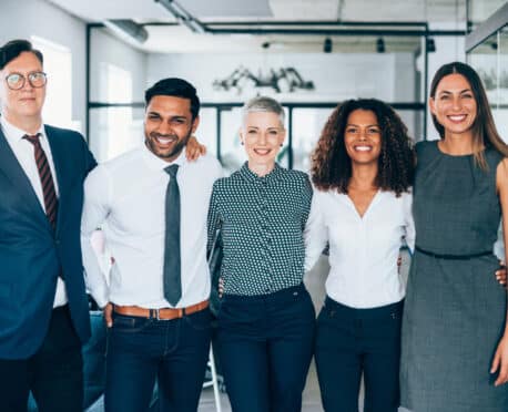 team of five young professionals standing in office setting