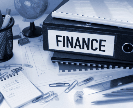 Desk covered with items including binder marked FINANCE