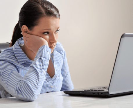 Disappointed looking young woman looking at laptop computer screen