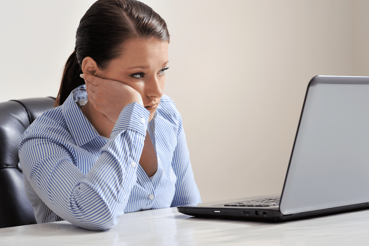 Disappointed looking young woman looking at laptop computer screen