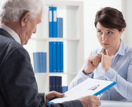 young executive woman being interviewed by older executive man