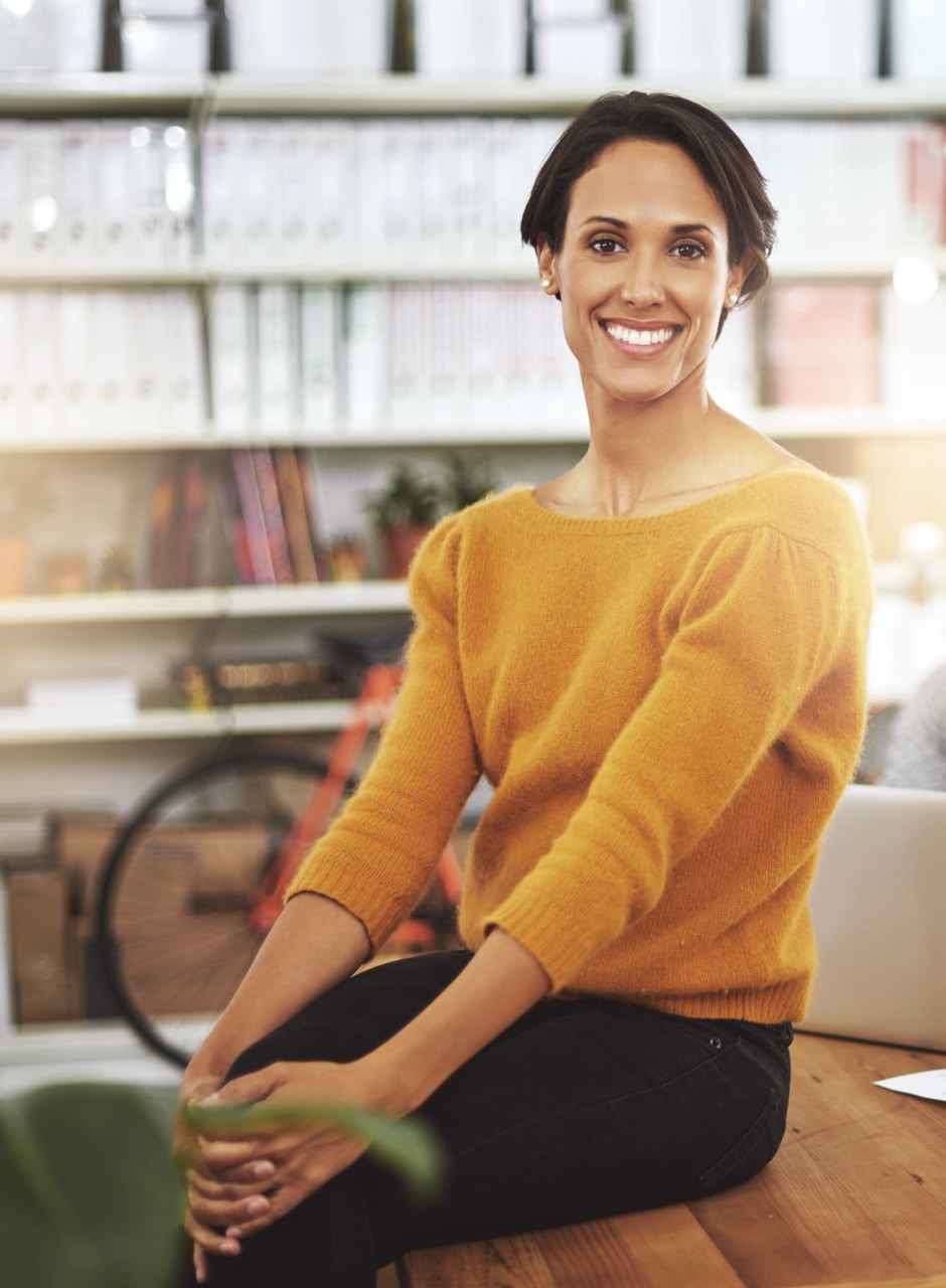 young executive woman sitting on desk in office