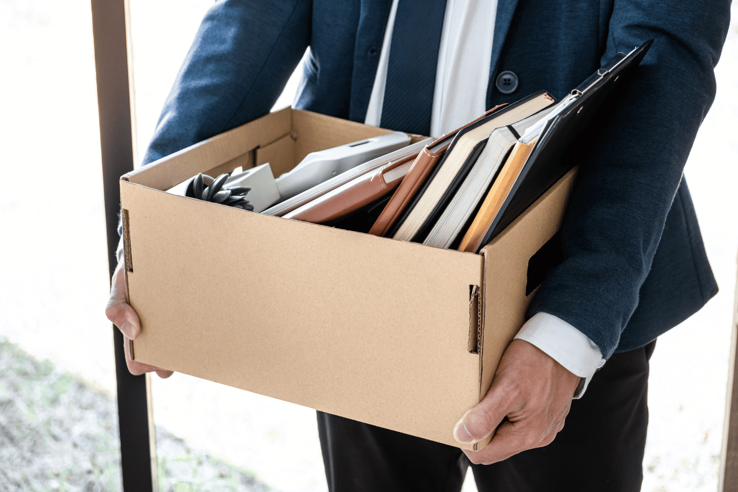 Man leaving his job carrying a box of items from his desk