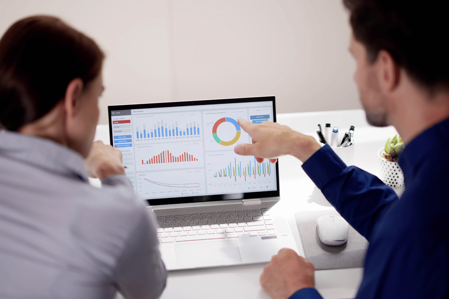 Two businessmen reviewing financial analytics dashboard on computer screen.