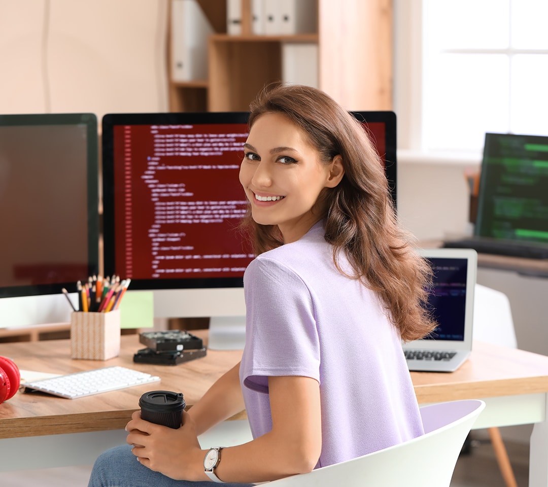 young female programmer sitting in front of computer screens