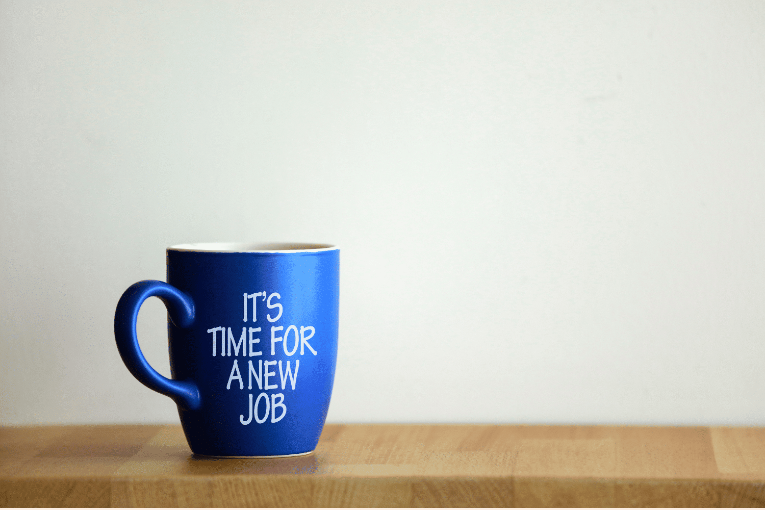 Blue coffee cup on table that says "It's time for a new job"