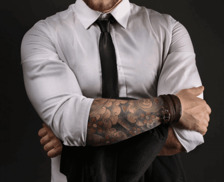 Young professional male with arms folded and sleeves rolled up, revealing extensive tattoos