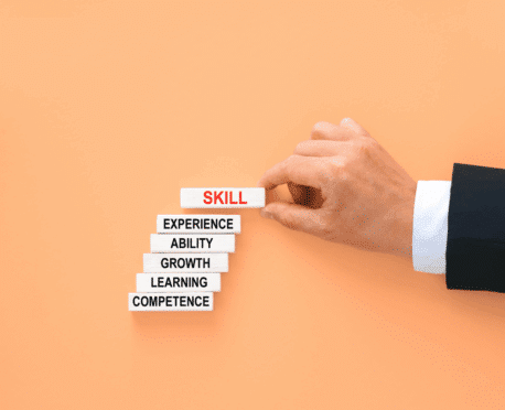 Business leader hand arranging wooden blocks labeled competence, learning, growth, ability, experience, and skill, symbolizing skills-first executive search and outcome-based leadership hiring for Oggi Talent’s blog.
