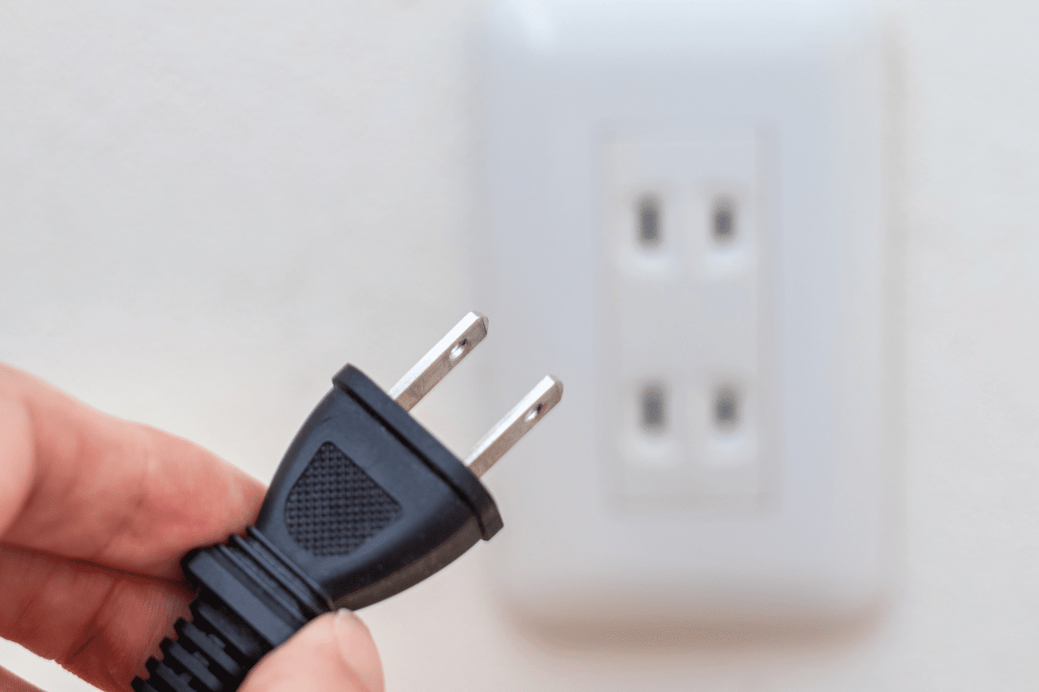 Hand holding a power cord toward a socket, illustrating how Oggi Talent’s executive search as a plug-in capability allows growing firms to instantly activate a professional recruitment engine without the overhead of internal infrastructure.