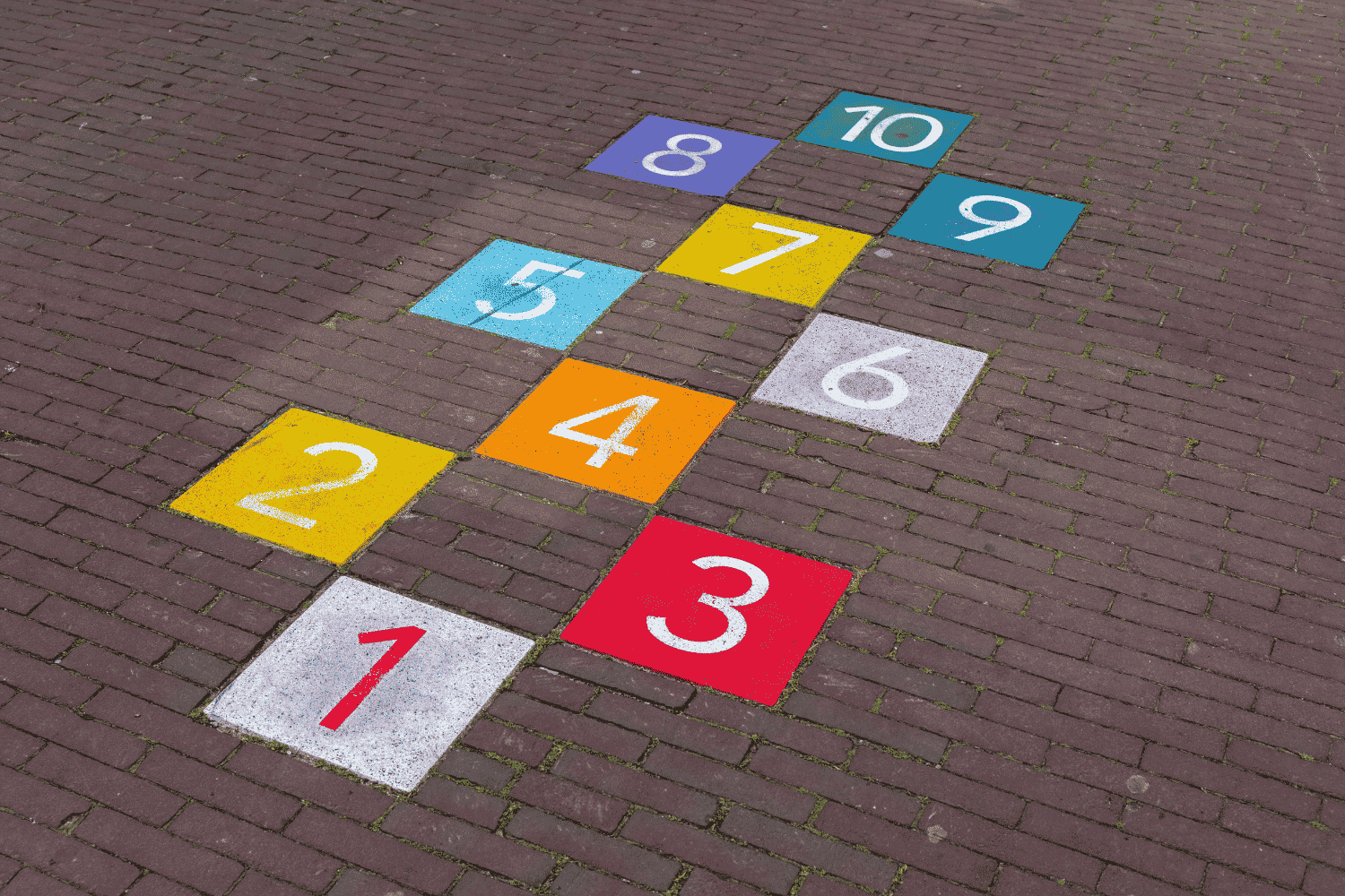 Colorful hopscotch path on brick pavement symbolizing job hopping, career progression, and executive candidate evaluation