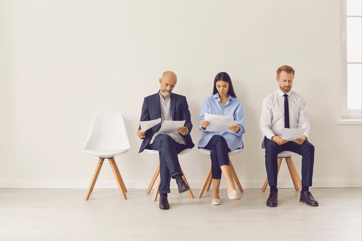 Three finance executive candidates review resumes beside an empty chair, illustrating the choice between hiring a Controller, VP of Finance, or CFO.