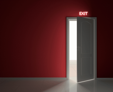 Open exit door beneath a glowing exit sign, symbolizing executive turnover and why senior leaders quit their jobs